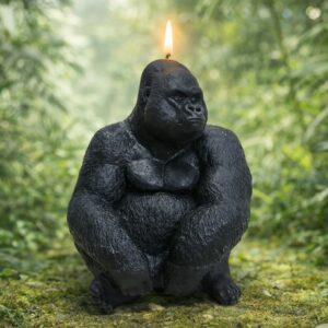 Bougie artisanale noire en forme de gorille allumée dans un décor de jungle verdoyante
