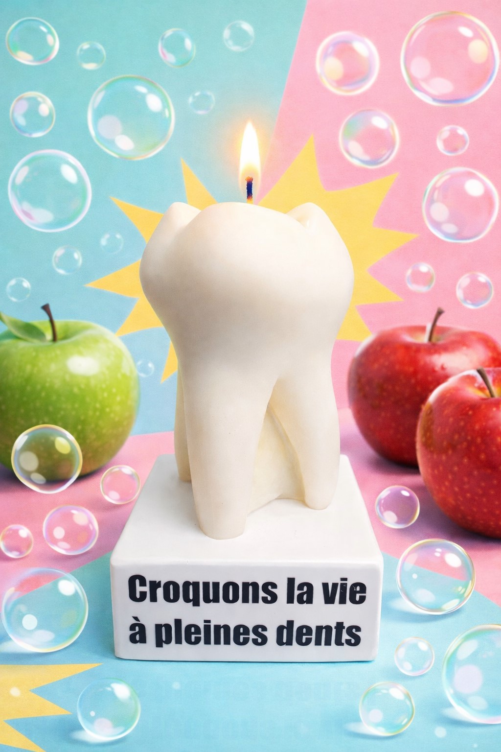 Bougie insolite en forme de dent avec flamme, mise en scène pop art vitaminée avec pommes colorées et fond pastel graphique